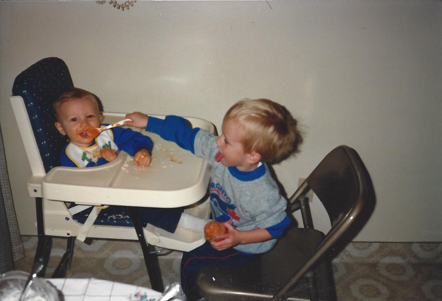 Bentley feeding baby Parker in a high chair